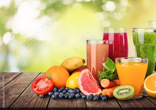 Fototapeta Naklejka Na Ścianę i Meble -  Composition of fruits and glasses of juice on blurred natural background