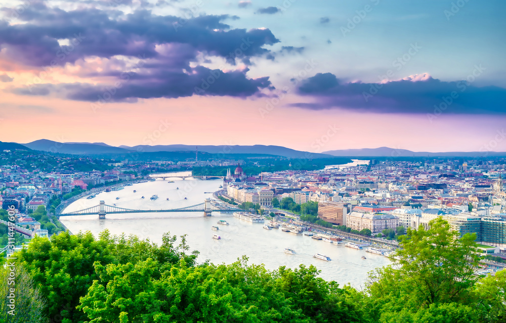 Obraz premium A view along the Danube River of Budapest, Hungary from Gellert Hill at sunset.