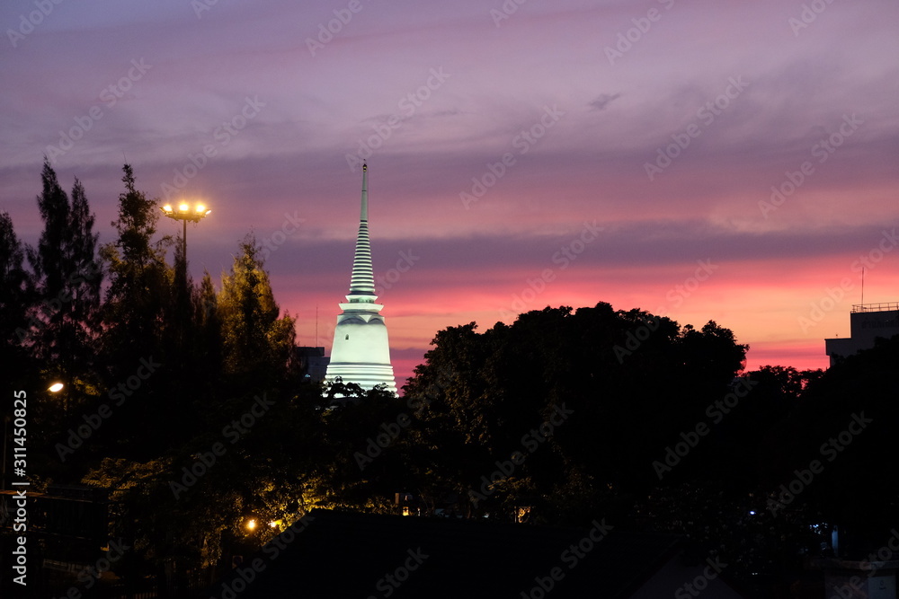 Beautiful sunset over the silhouettes of trees. Lighted spire of a Buddhist temple. Beautiful sunset over the silhouettes of trees. Lighted spire of a Buddhist temple.