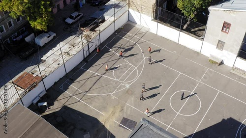 Group of kids play soccer football on blacktop court bird's eye view drone 4K