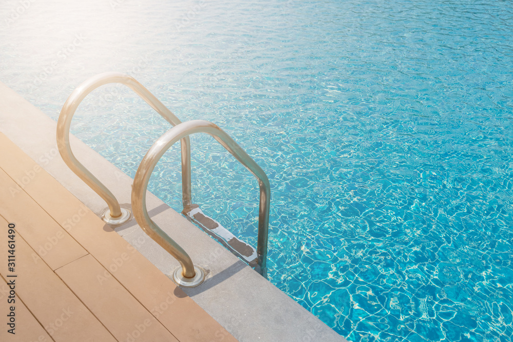 Stairs Ladder and handle down the swimming pool with blue water Stairs Ladder and handle down the swimming pool with blue water