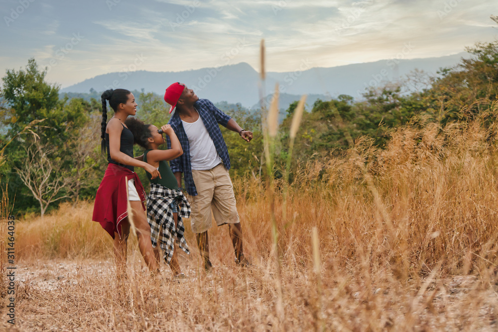 Obraz premium african american family, father, mother and daughter, having fun with birds watching activity together in natural forest
