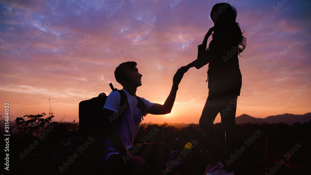 silhouette of man having married engagement proposal to woman during romantic moment of sunset outdoors