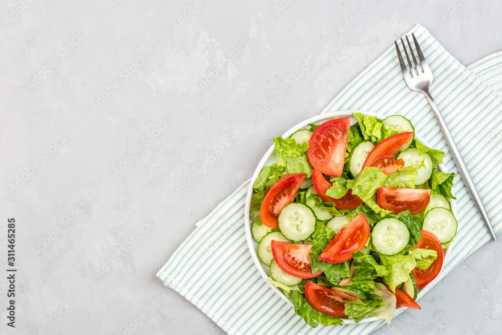 Healthy vegetarian dish on table, vegetable salad with fresh tomato, cucumber, lettuce, red onion on gray concrete background. Diet menu. Top view. Flat lay, mockup, template with copy space Healthy vegetarian dish on table, vegetable salad with fresh tomato, cucumber, lettuce, red onion on gray concrete background. Diet menu. Top view. Flat lay, mockup, template with copy space