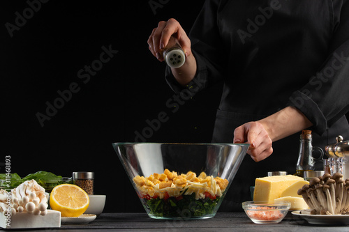 A cook sprinkles Italian seasoning in a salad