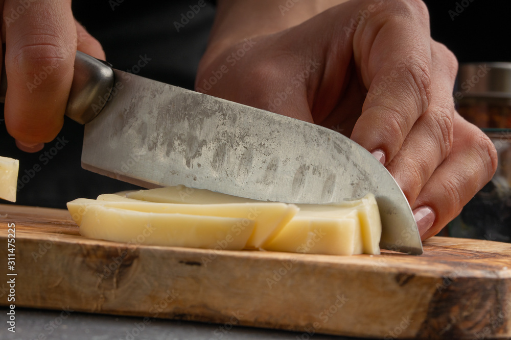 Professional chef slices cheese closeup, macro