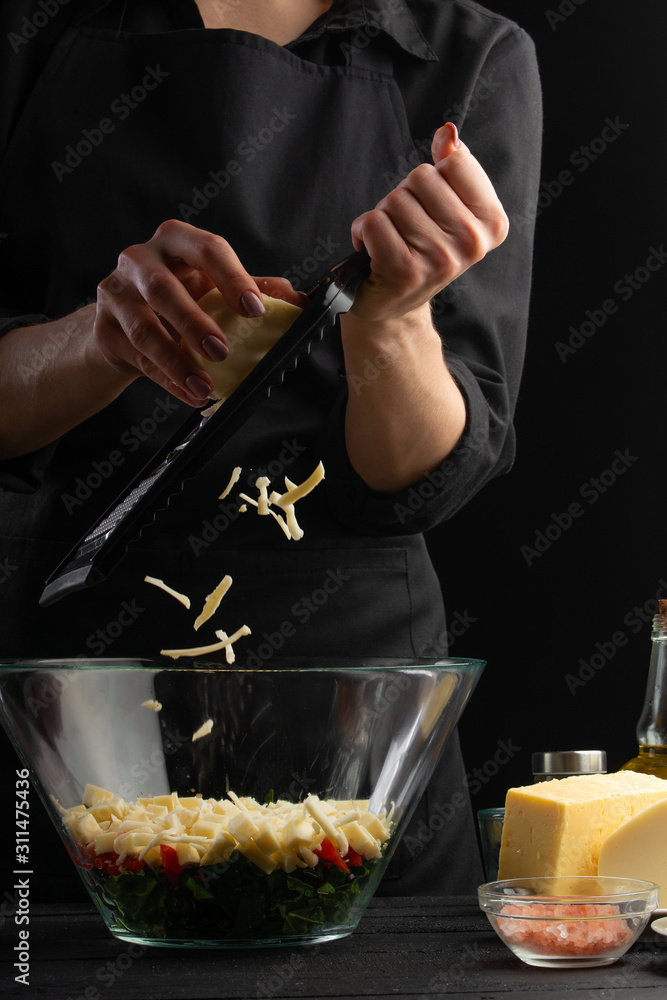 A professional chef cooks a fresh and healthy Italian salad grating mazarella cheese, Freezing in motion. Organic and wholesome food. Healthy nutrition and vitamins. Vertical shot.