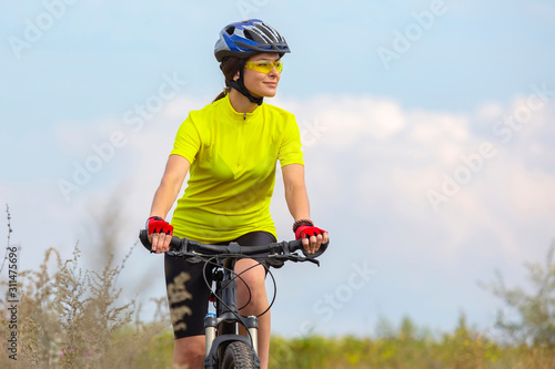 Beautiful girl in yellow riding a bike in nature. Sports and recreation. Hobbies and health.