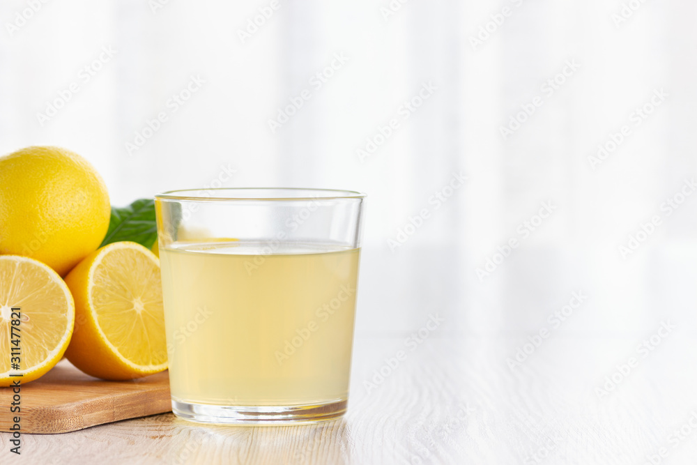 A glass of lemon juice and lemons on a table. A glass of lemon juice and lemons on a table.