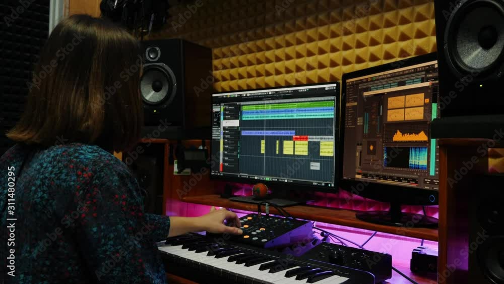 Female musician songwriter playing piano midi keyboard in recording