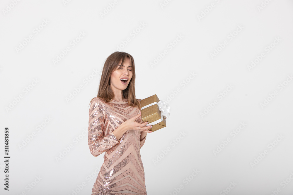 Beautiful girl with a gift expresses emotions on a pink background. Christmas concept. Mockup. Soft focus. Beautiful girl with a gift expresses emotions on a pink background. Christmas concept. Mockup. Soft focus.