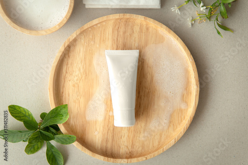 Schilderij op canvas Top view of Organic gentle cleanser tube on a wooden plate decoration with leaves and white flower on grey background