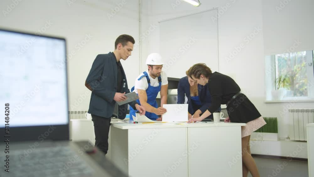 Builder in uniform and group of engineers discuss schemes of houses Builder in uniform and group of engineers discuss schemes of houses