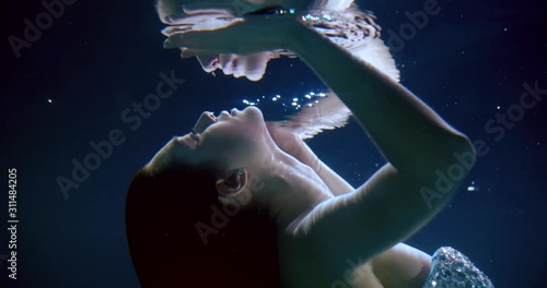 young woman is approaching to reflection of her face underwater