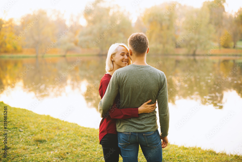 Photo of happy young couple embracing at sunset near lake during autumn Photo of happy young couple embracing at sunset near lake during autumn