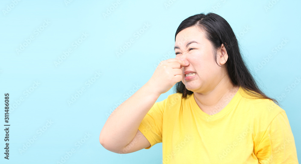 portrait Asia woman feels foul, on blue background in studio With copy space. portrait Asia woman feels foul, on blue background in studio With copy space.