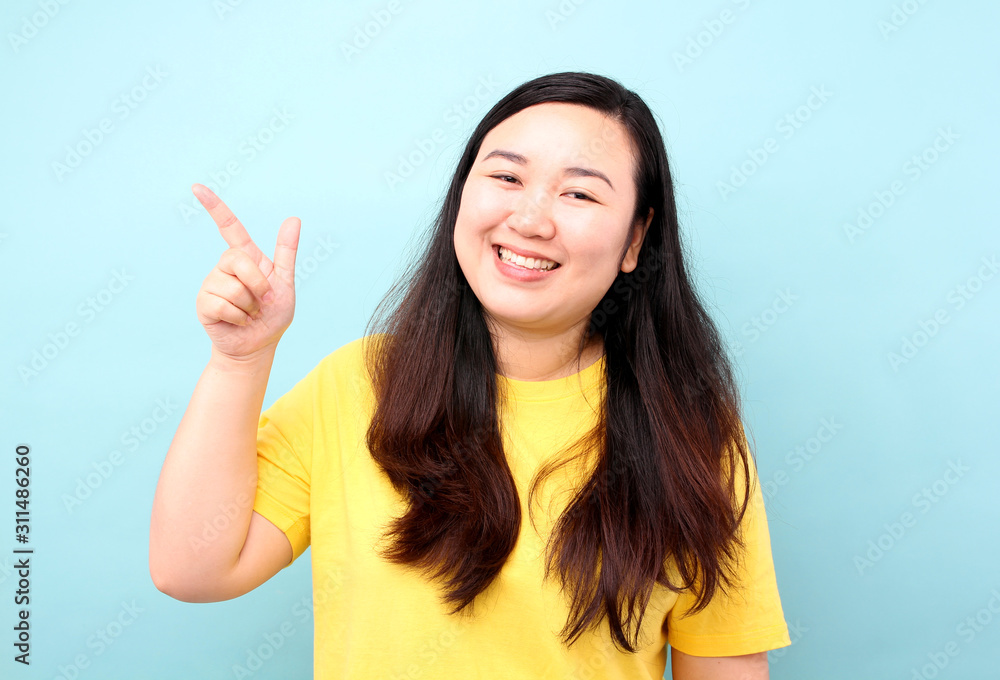 Portrait Asia women with a finger, on A blue background in studio. Portrait Asia women with a finger, on A blue background in studio.