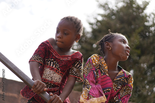 Two Little African Girls Making Efforts To Pump Water From The Public Borehole