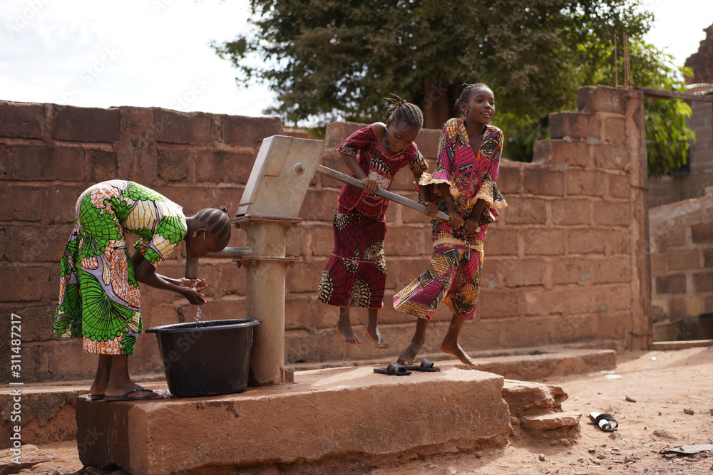Three African Girls Showing Off Teamwork Skills Collecting Water At a Borhole Hand Pump