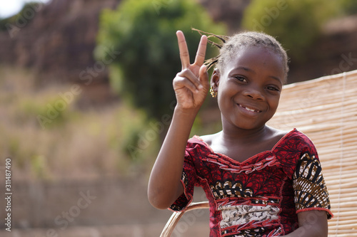 Adorable Small African Girl In Traditional Clothes Making The Peace Sign