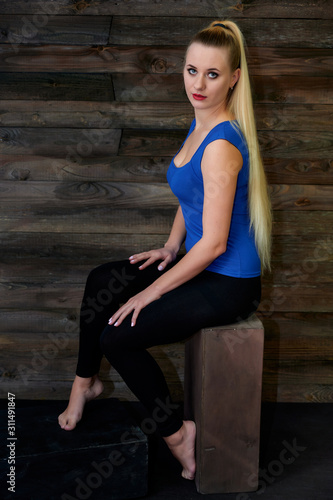 Art concept of a stylish model portrait. Portrait of a slender woman with long beautiful hair and excellent make-up on a creative background of wood in the loft style.