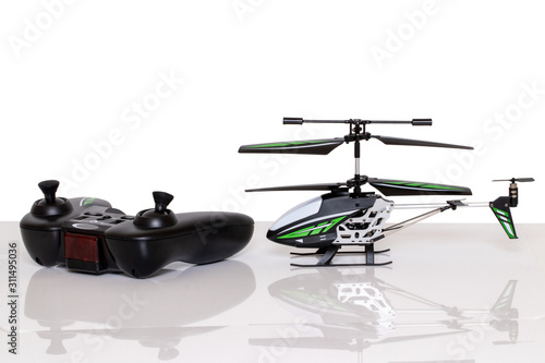 Closeup of a little RC toy helicopter and a remote controller on a bright table isolated on a white background. Macro photograph of remote controlled helicopter.