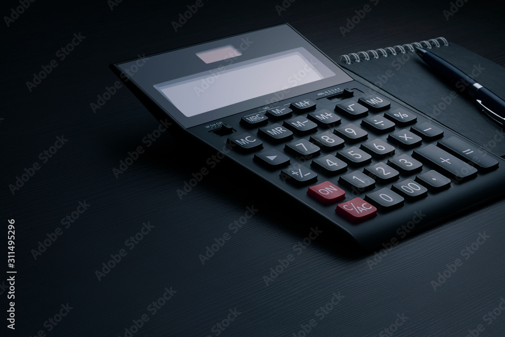Side view of a black accounting calculator with blank screen, pen and notebook on a dark wooden office desk with copy space. Business and finance template. Tax and profit calculation concept Side view of a black accounting calculator with blank screen, pen and notebook on a dark wooden office desk with copy space. Business and finance template. Tax and profit calculation concept