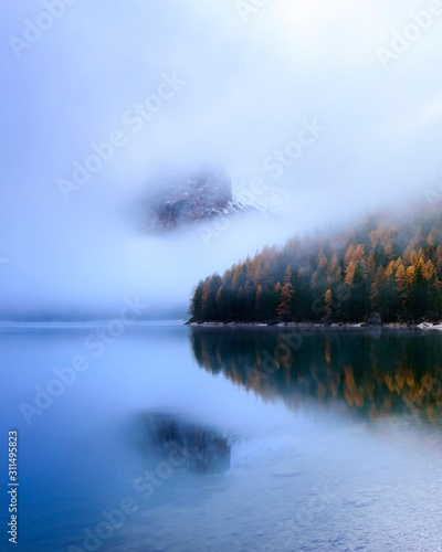 Dolomites Reflection in water in Lago di Braies (Braies lake, Pragser wildsee) South Tyrol, Italy ; Foggy morning high ISO photography