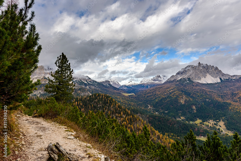 Colourful forest and Dolomite mountains surrounded by clouds in South Tyrol, Italy /View from Lago di Sorapis hiking trail / High ISO image Colourful forest and Dolomite mountains surrounded by clouds in South Tyrol, Italy /View from Lago di Sorapis hiking trail / High ISO image