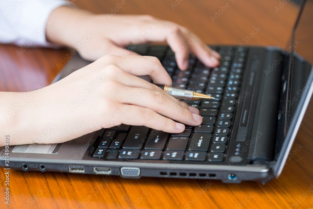 A businesswoman with a pen is using a laptop in her office. A businesswoman with a pen is using a laptop in her office.