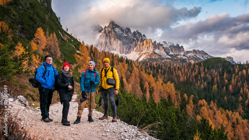 Team of travellers dressed in colourful jackets standing on the ''lago di sorapis'' trail in Italian alps /  Dolomite mountains in background during sunset / High ISO image