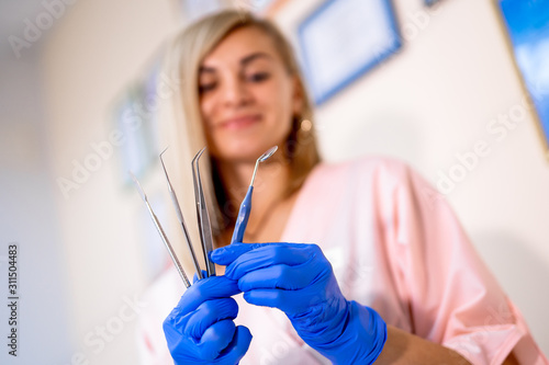 dental instruments. Dental tools in hand. Professional woman dentist doctor working. Blurred background. Closeup