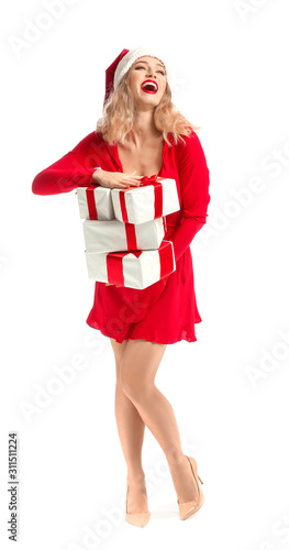 Beautiful young woman in Santa hat and with Christmas gifts on white background