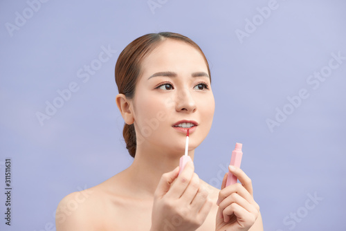 Pretty trendy stylish girl testing new lip gloss isolated on violet background  perfection  wellbeing advertisement concept