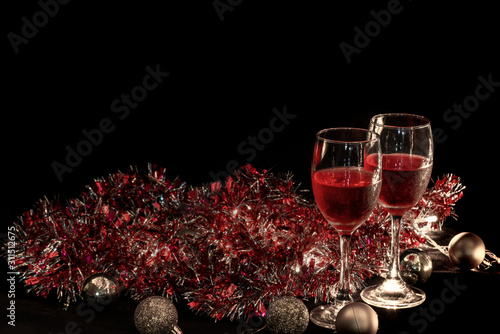 christmas atmosphere,two red wine glass against christmas lights decoration background.