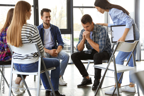 Psychotherapist working with patients in group therapy session indoors © New Africa