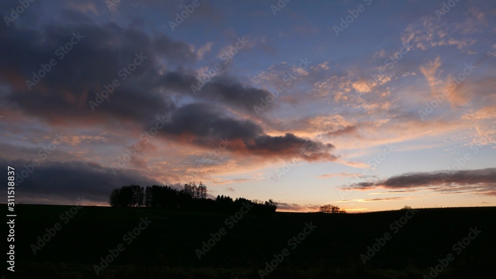 Sonnenuntergang im Winter über Wald und Feldern