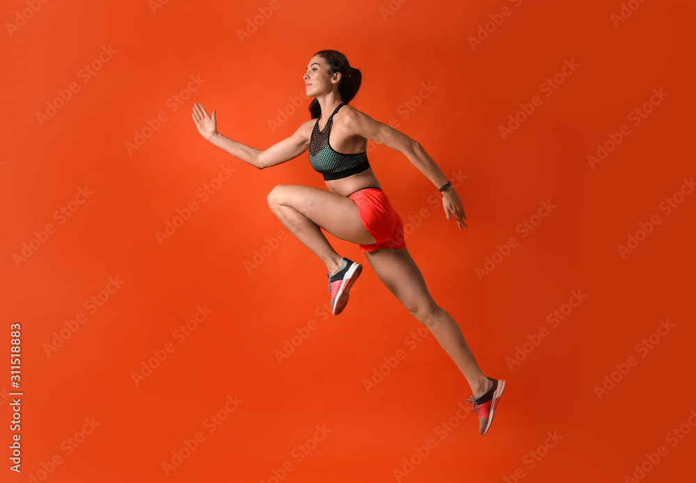 Athletic young woman running on red background, side view