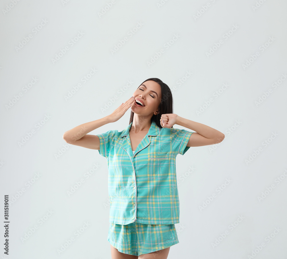 Beautiful Asian woman in pajamas yawning on light grey background. Bedtime Beautiful Asian woman in pajamas yawning on light grey background. Bedtime