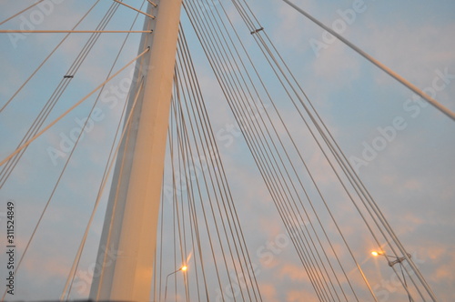 beautiful evening blue sky with pink clouds, gray pillars of different thicknesses and tilts and luminous lights