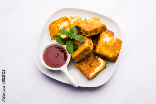 Amritsari Paneer Tikka made using cottage cheese cubes dipped in a batter made with besan, chat masala and spices and shallow fried in pan, served with ketchup