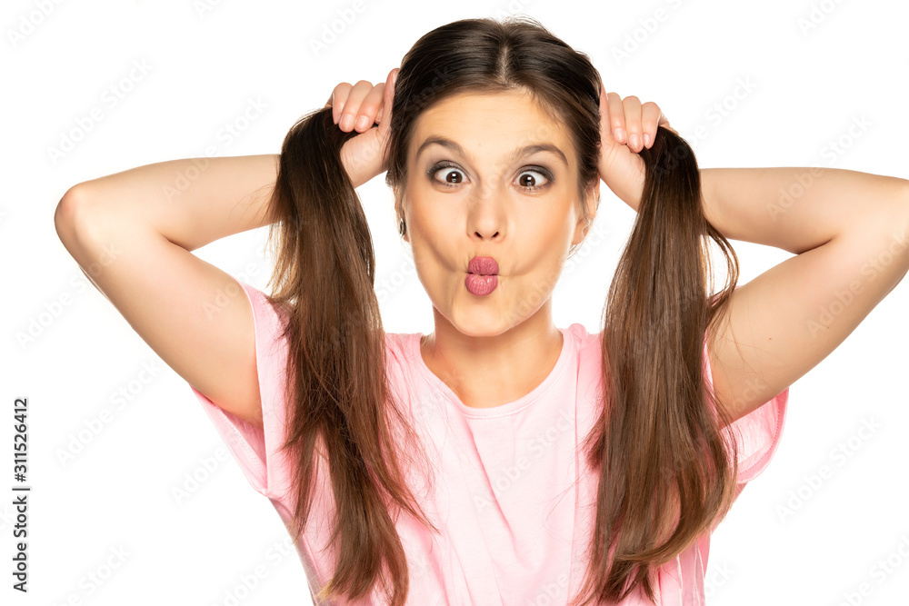 Young funny woman with ponny tails make a faces on white background Young funny woman with ponny tails make a faces on white background