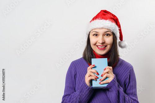 portrait of a young woman in a Christmas hat with a gift in her hands.