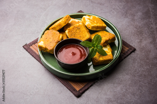 Amritsari Paneer Tikka made using cottage cheese cubes dipped in a batter made with besan, chat masala and spices and shallow fried in pan, served with ketchup