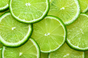 Close-up juicy Lime slices abstract background in pastel green color. Bright summer texture.
