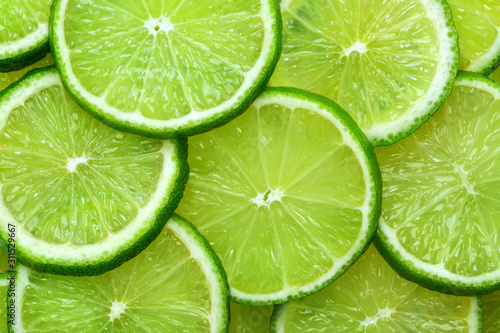Close-up juicy Lime slices abstract background in pastel green color. Bright summer texture.