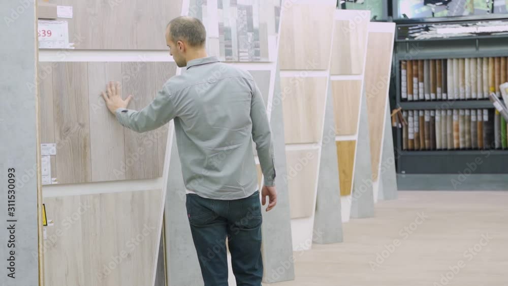 Man choosing laminate samples in hardware store Man choosing laminate samples in hardware store