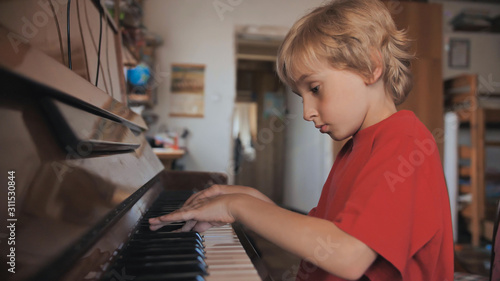 A boy of seven plays the piano at home.