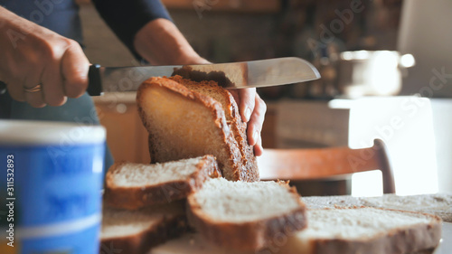 Cooking breakfast. A young woman cuts bread.