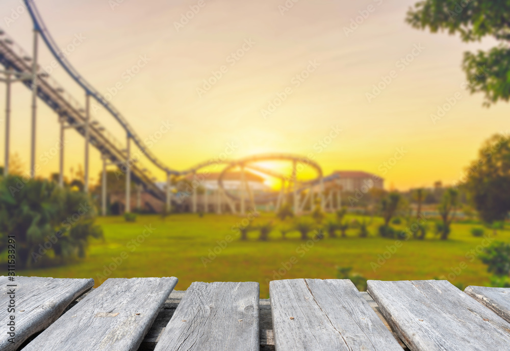 Fototapeta premium Empty wooden table top on the blur background of roller coaster in amusement park